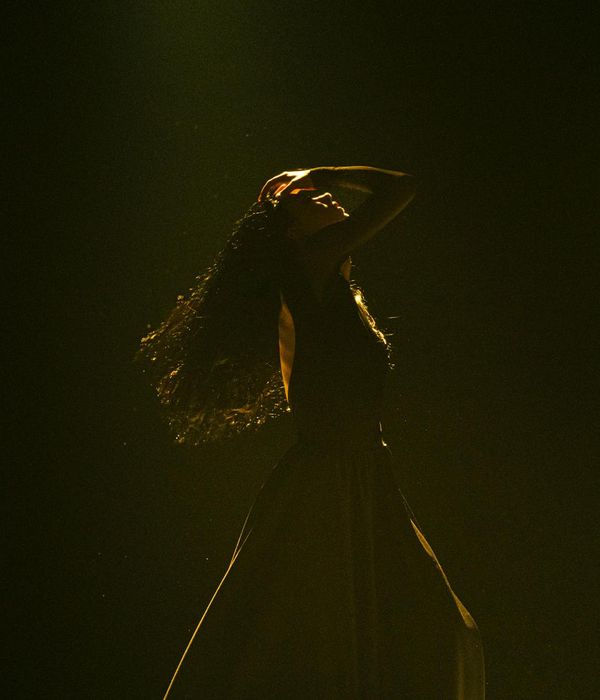 Woman in a dynamic, fluid motion pose against a dark background.